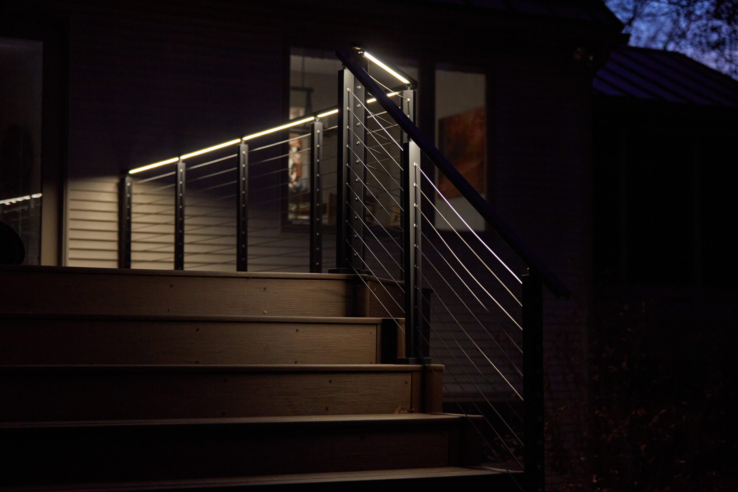 Cable railing with LED handrail Cable railing with LED under-lit handrail on a deck at night