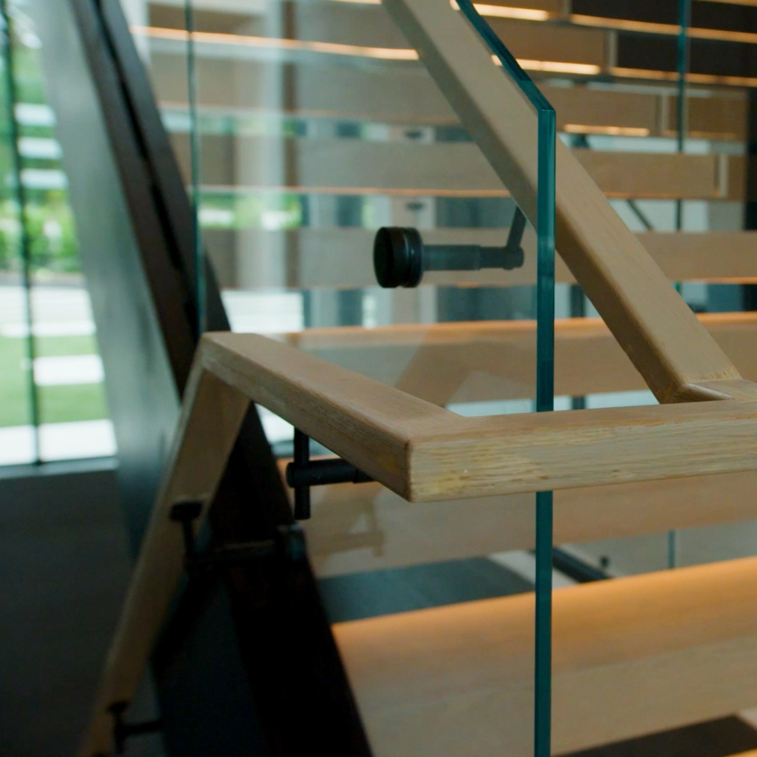 Close up of the continuous handrail atop the glass railing featured on the FLIGHT Blade stair system.