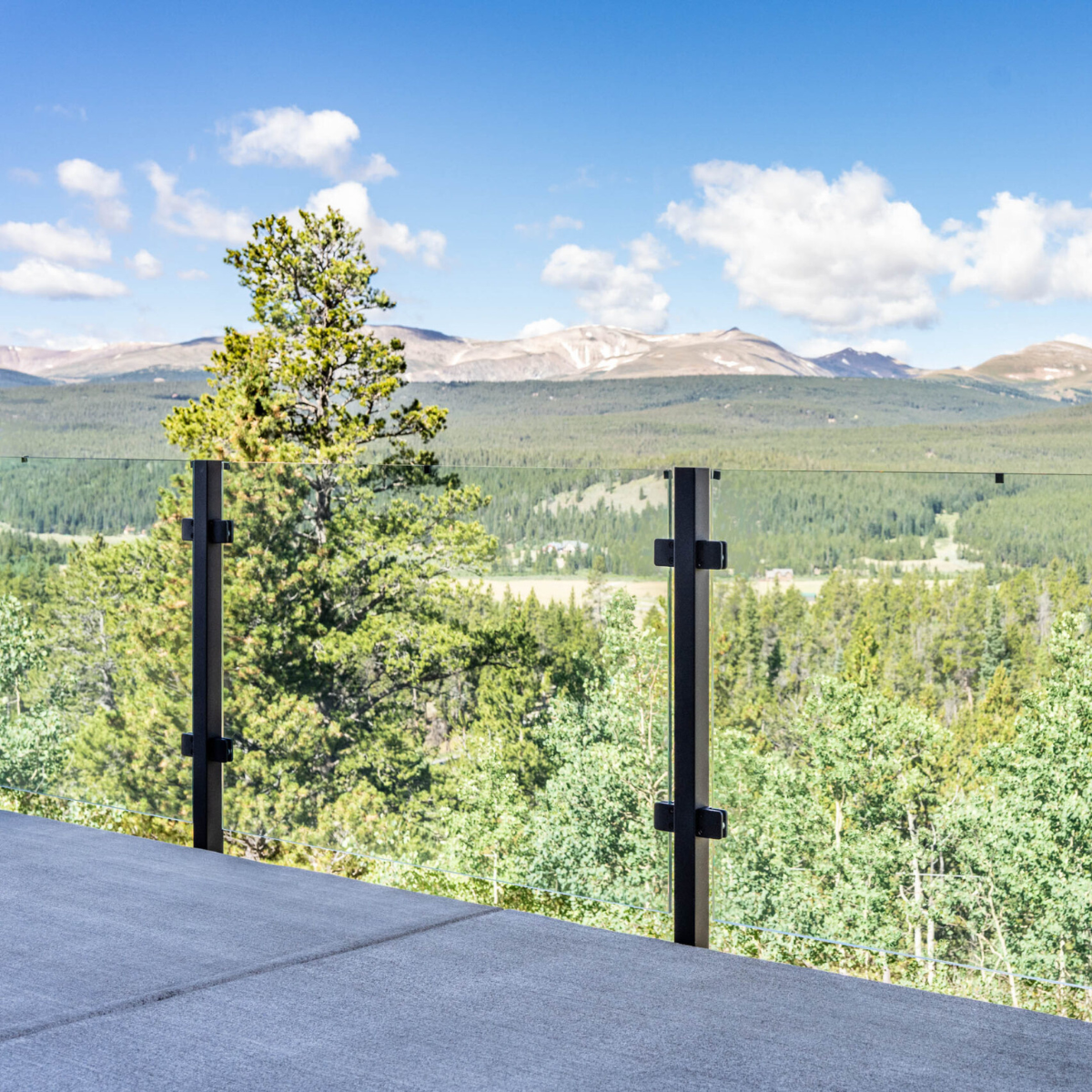 Exterior glass railing using laminated glass overlooking a mountain and forests