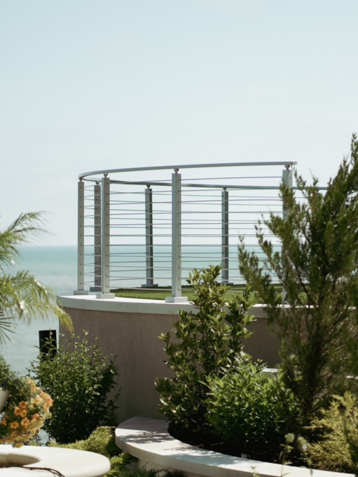 An exterior Signature railing with stainless posts and curved stainless rod railing.