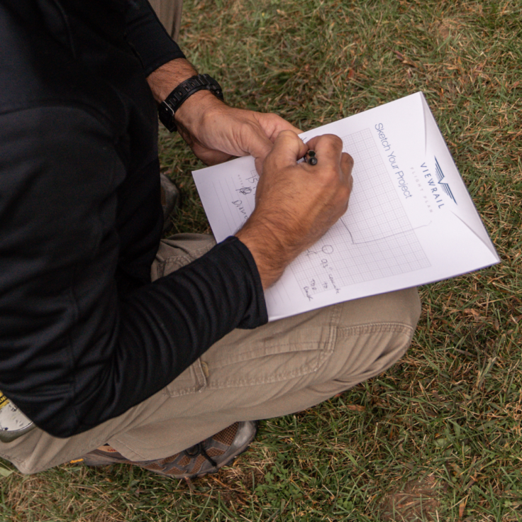 A man leans down and records measurements on a sheet of paper