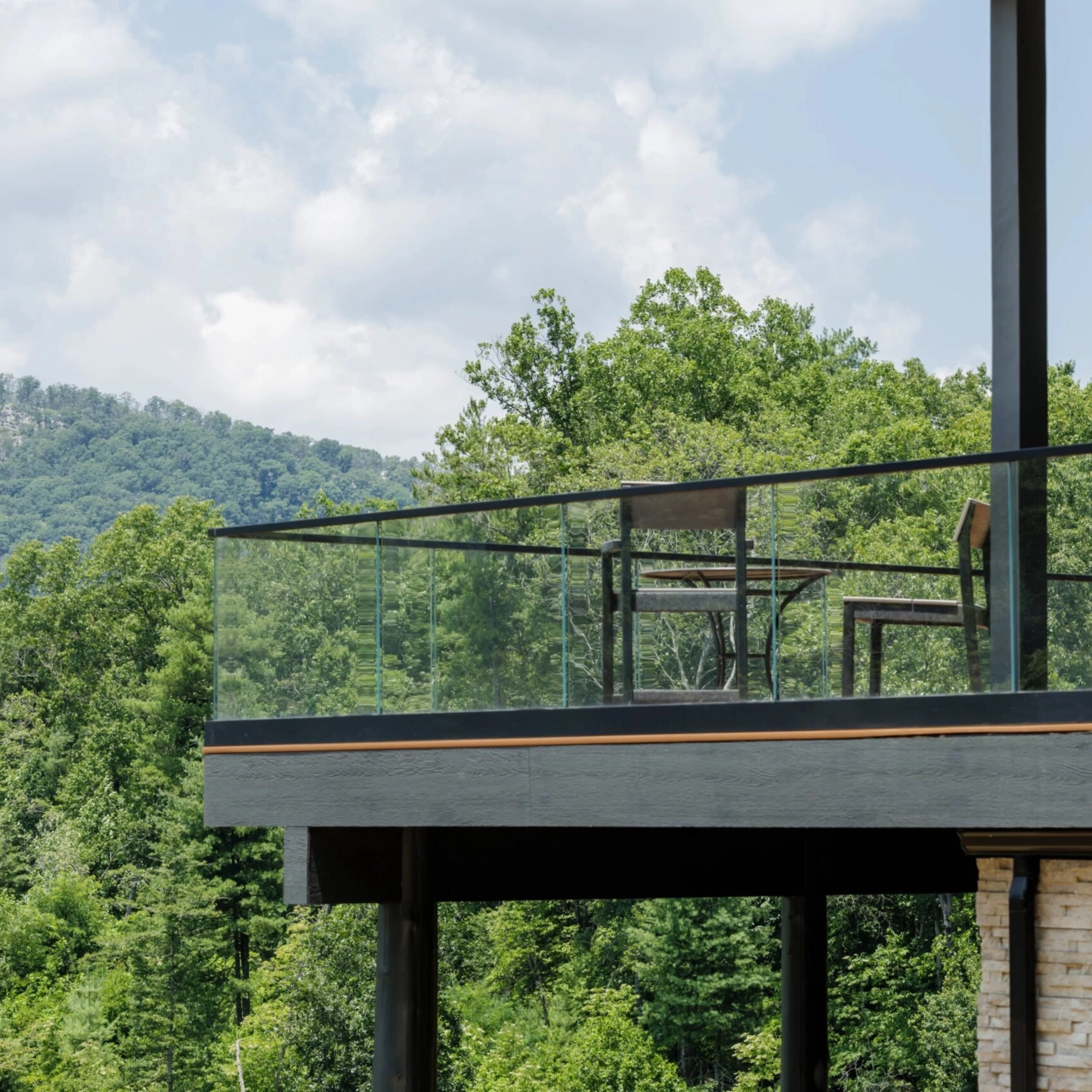 Base Rail on a second-floor patio overlooking a large forest.