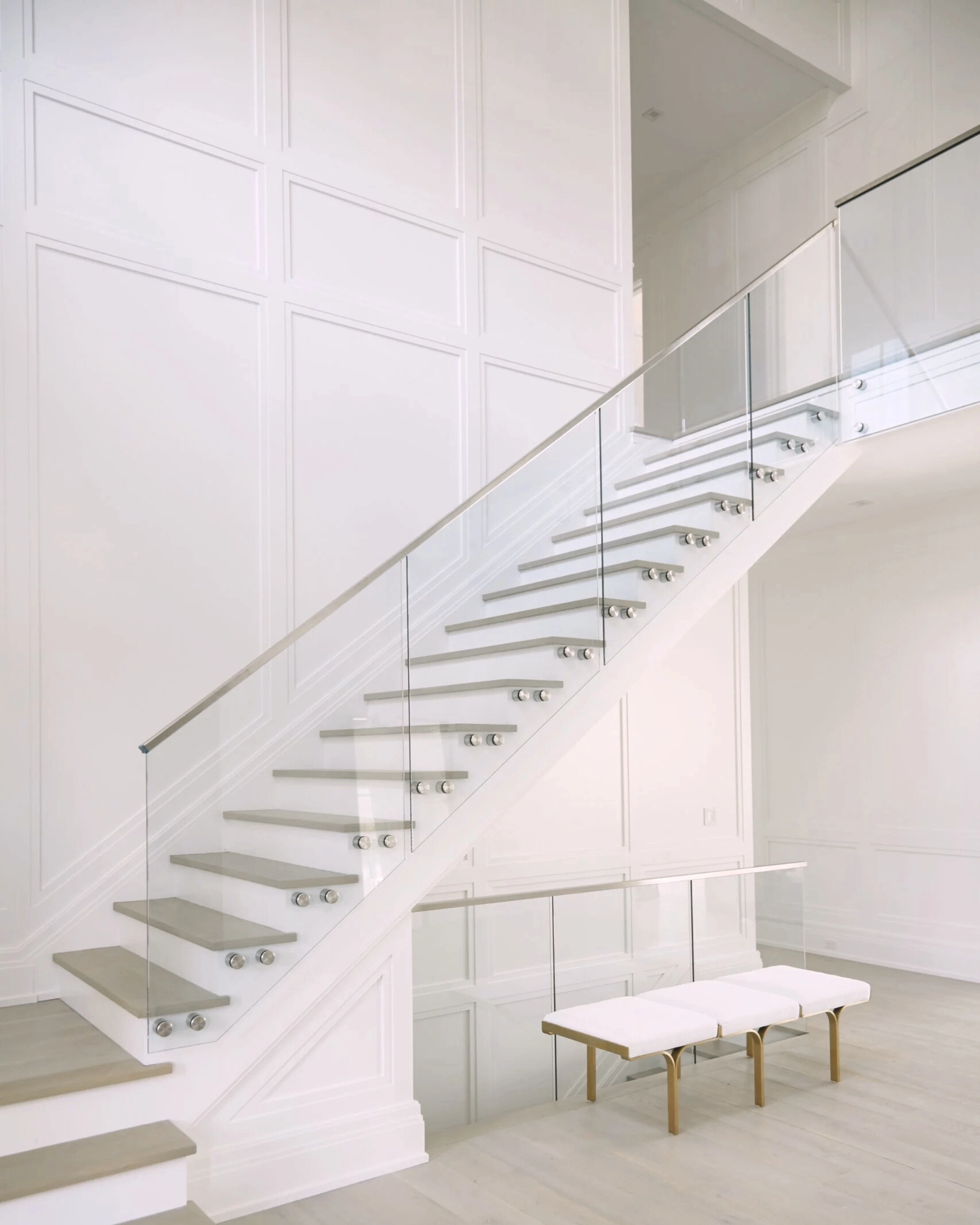 A Standoff Pins glass system graces the side of a tall staircase and continues on the landing.