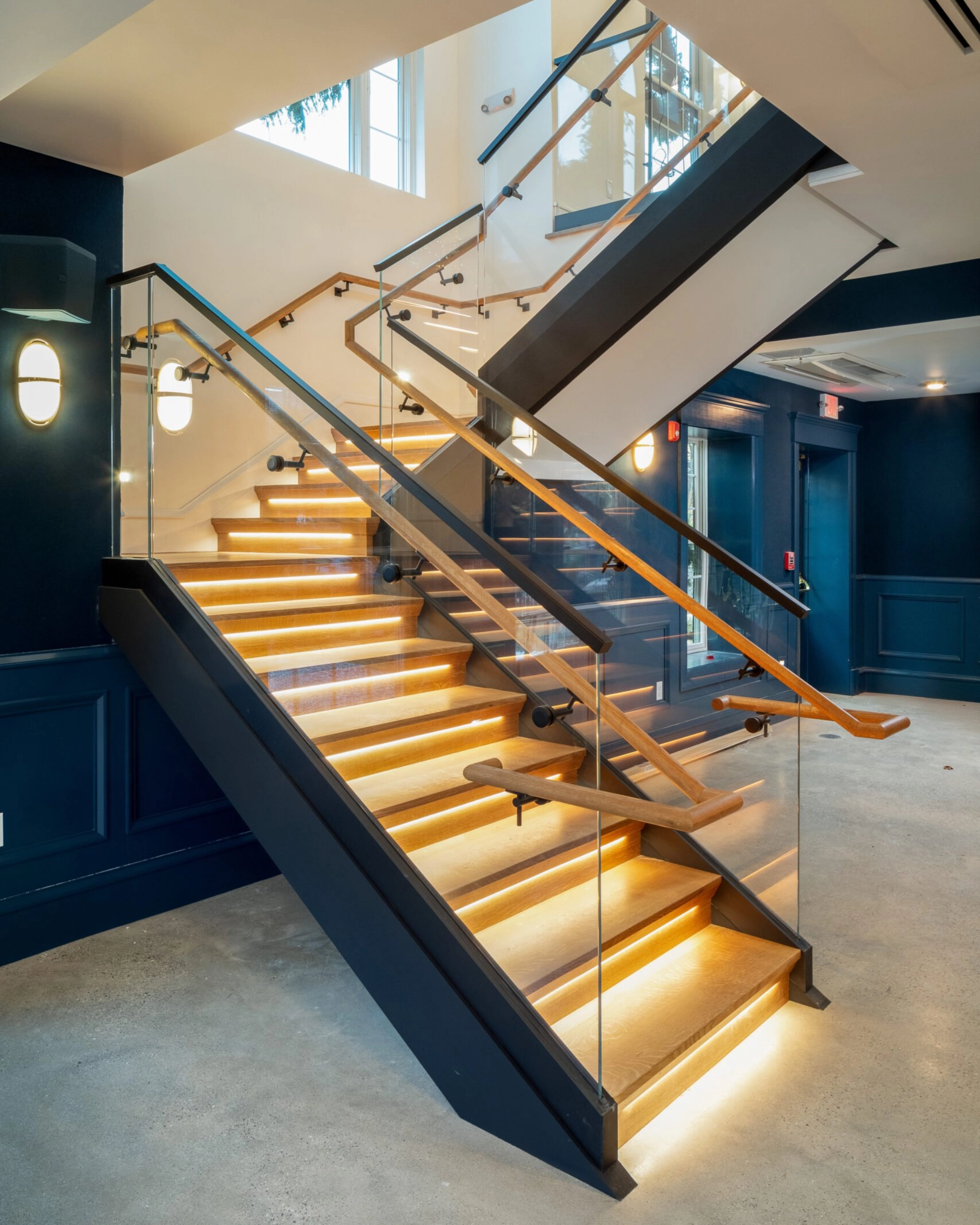 Base Rail ascends a stairway with a glass-mounted handrail.