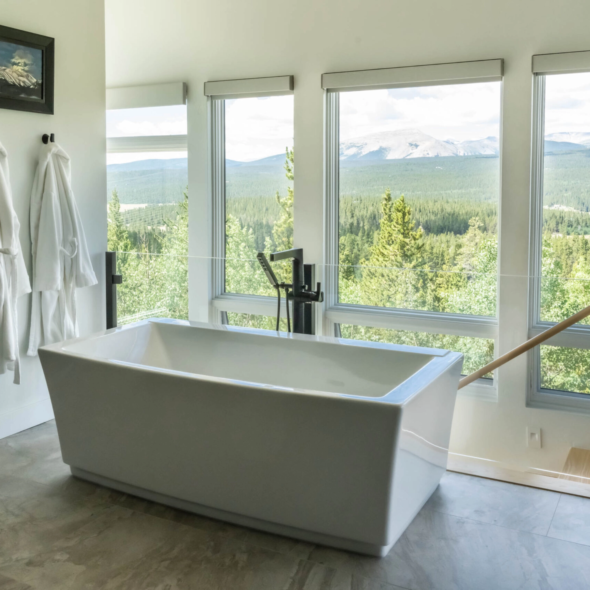Glass post system set behind a modern bathtup with sweeping views visible through large windows.
