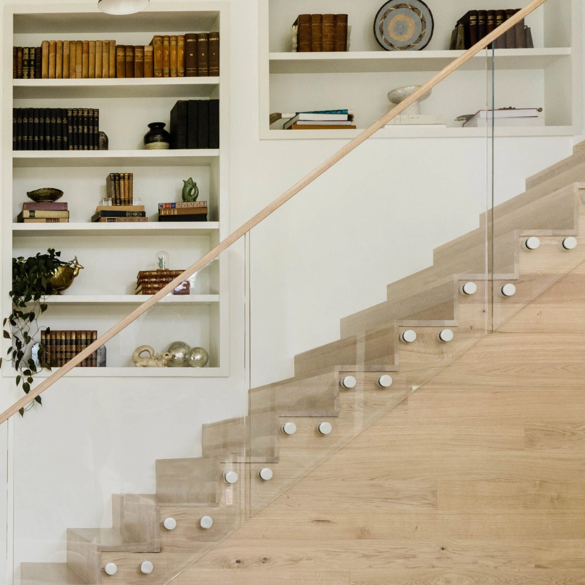 Standoff pins on a traditional staircase in from built-in bookshelves.