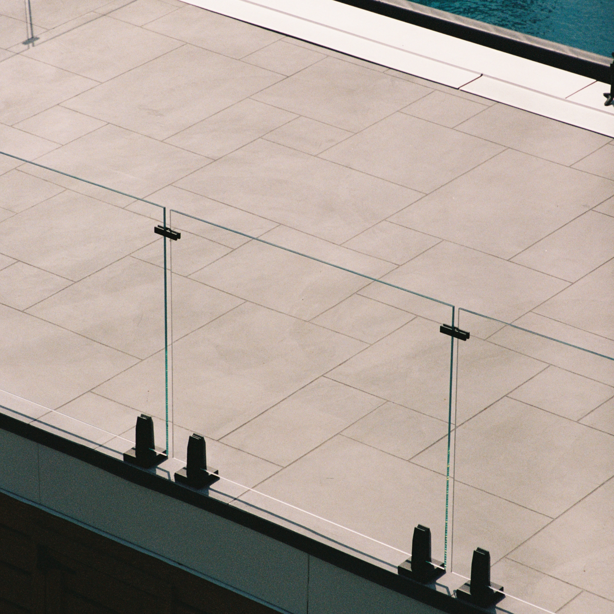 Talon Spigots securely hold glass railing with no top cap on a poolside patio.